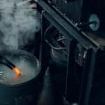 Blacksmith forges and tempering metal horseshoe in jar with water at forge